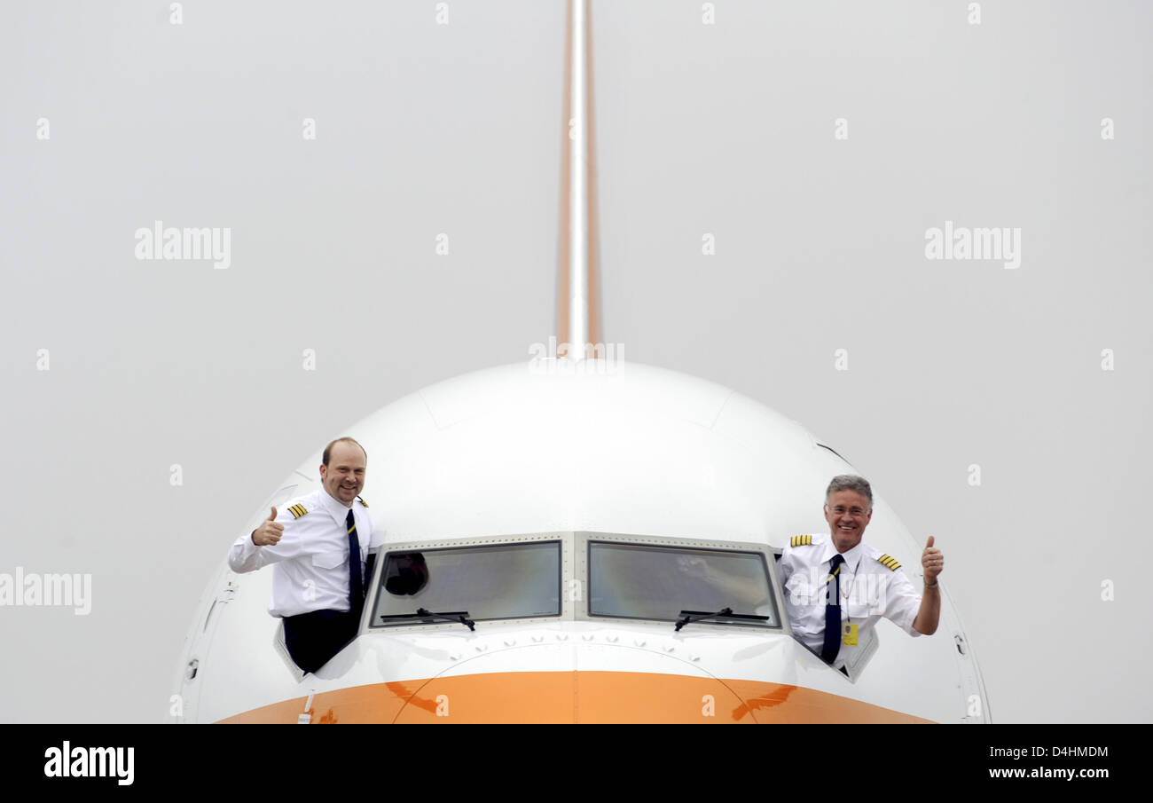 Captain Erik Olsen (R) and First Officer Sebastian Franz (L) give thumbs up out the cockpit of Boeing 737-800 ?Albert Ballin? of German tourism group Hapag-Llyod on the airport of Hamburg, Germany, 27 January 2009. Hapag-Lloyd offers a special kind of travel with luxury airplane ?Albert Ballin? that invites to a ?Cruise above the clouds?. A journey with the plane features German-sp Stock Photo