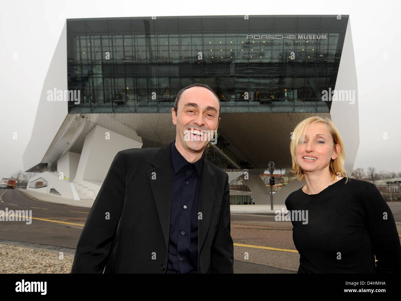 Architects Roman Delugan (L) and his wife and business partner Elke Delugan-Meissl (R) pose outside the building they designed during the inauguration of the new Porsche museum in Stuttgart, Germany, 28 January 2009. The futuristic building was inaugurated after three years of construction and will be opened for visitors on 31 January. A total of 82 of Porsche?s most relevant model Stock Photo
