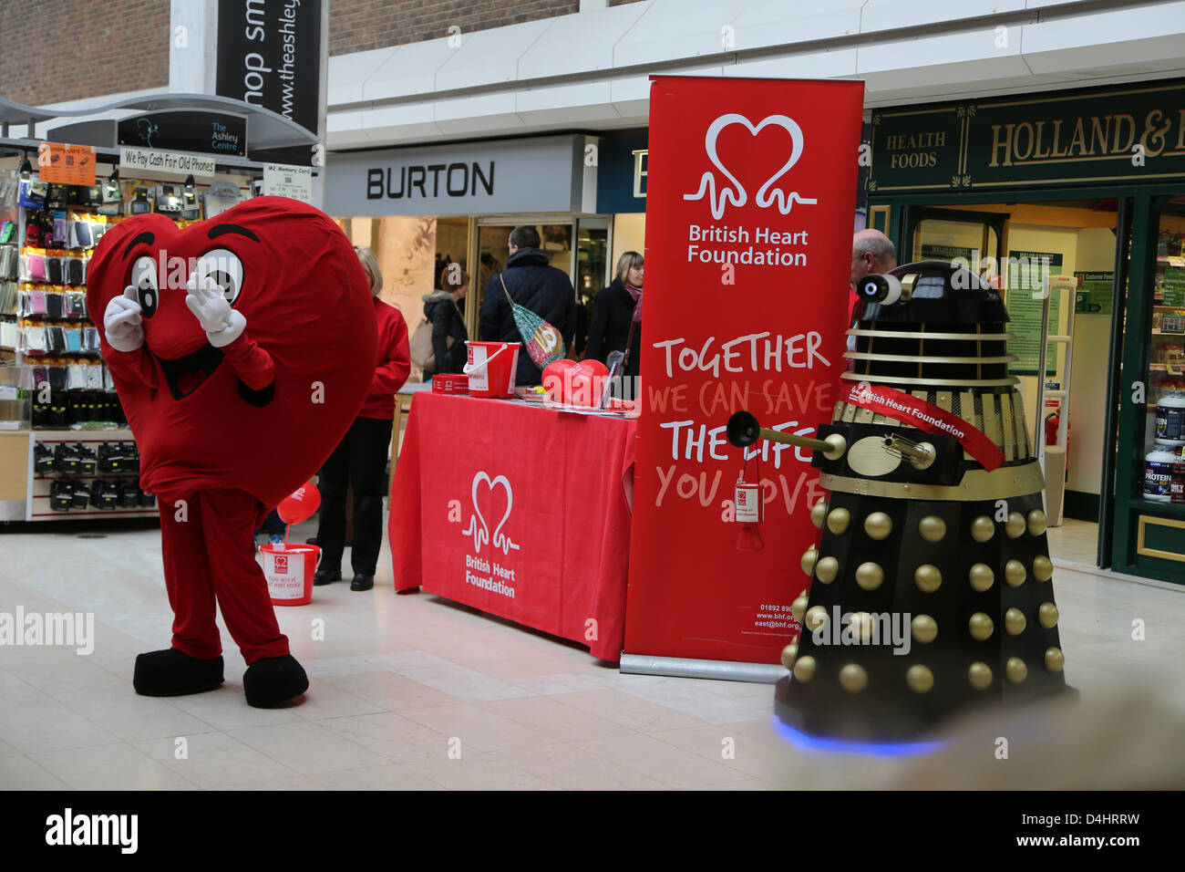 Person Dressed As A Heart And A Dalek From Doctor Who Next To A Stall For Raising Money For the British Heart Foundation Stock Photo