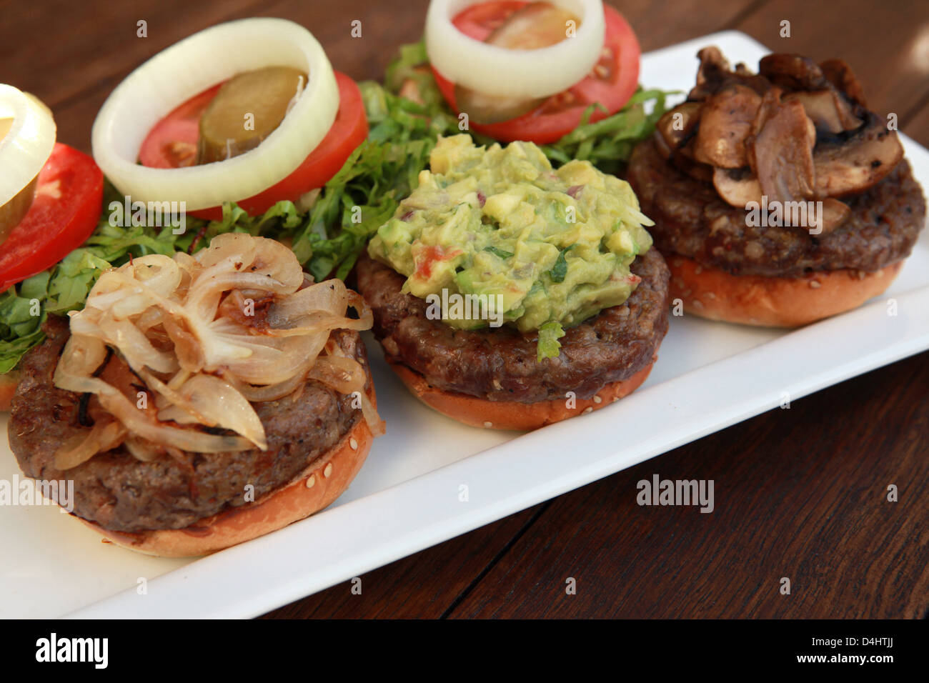 Three mini hamburgers with onions, guacamole and mushrooms Stock Photo