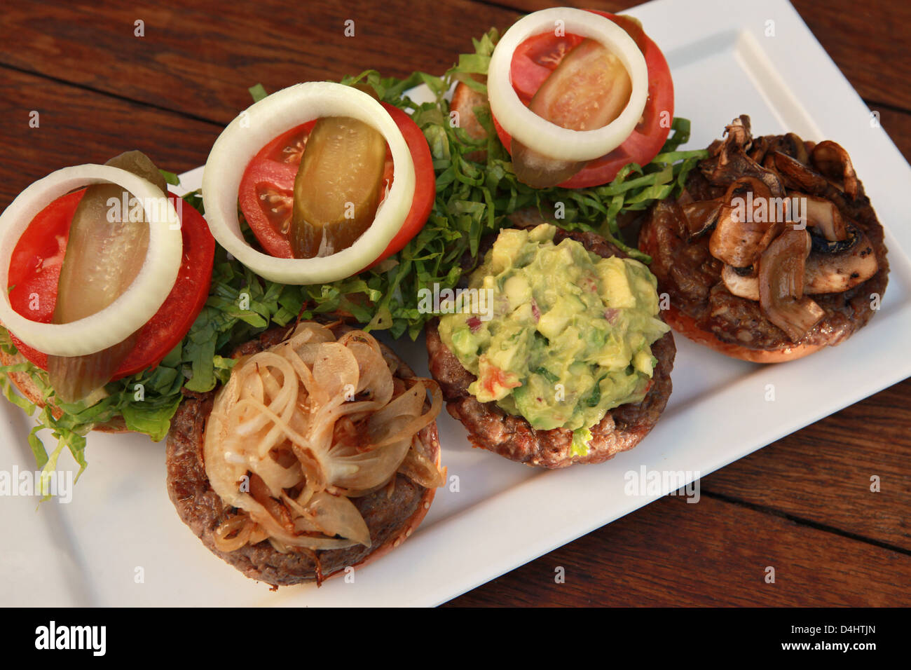 Three mini hamburgers with onions, guacamole and mushrooms Stock Photo
