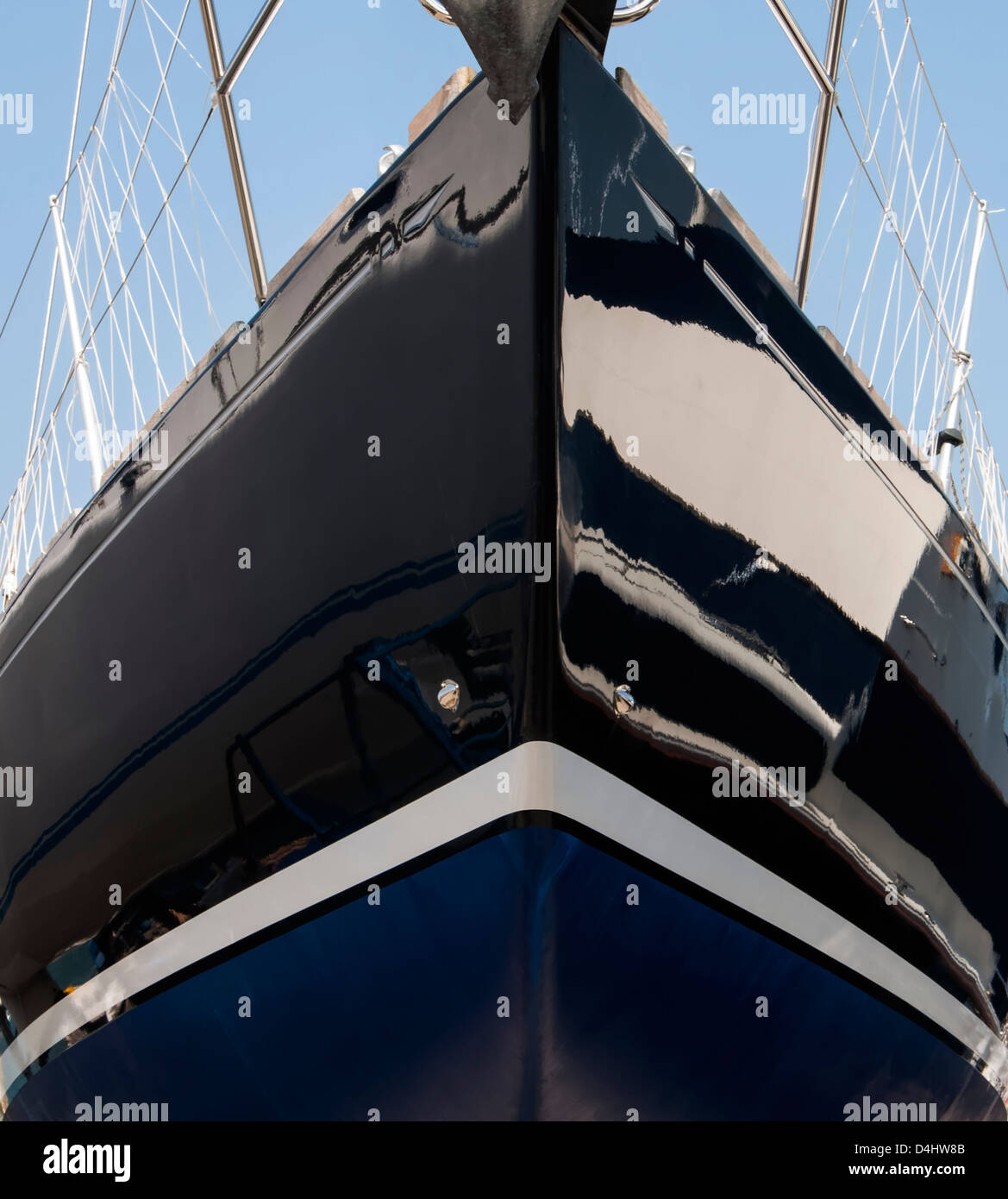Symmetrical close-up of yacht bow in dark blue glass reinforced plastic with white waterline stripe and blue anti-fouling paint Stock Photo