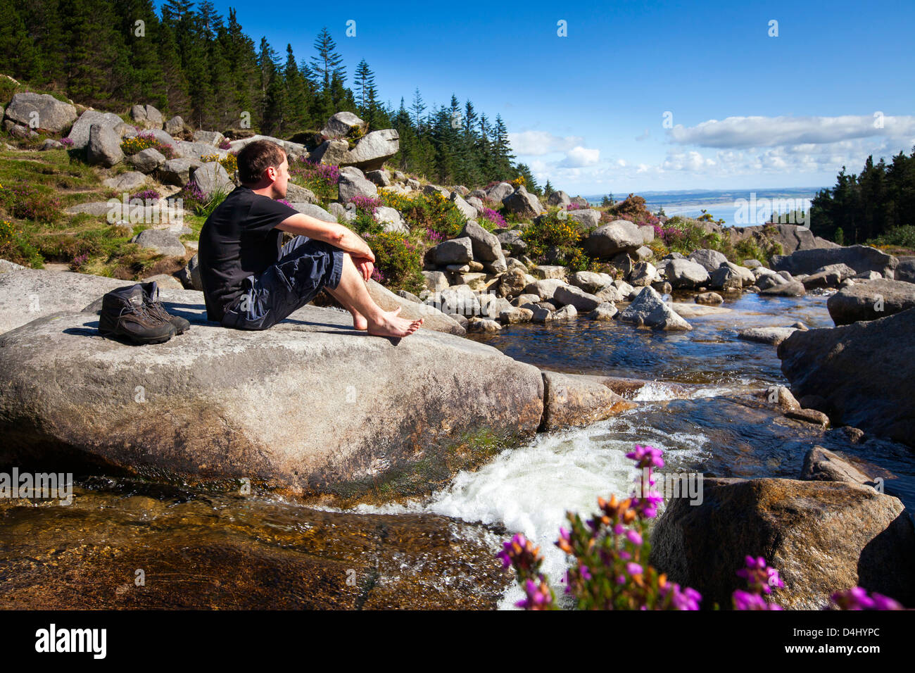 A hill walker resting at a river. Stock Photo