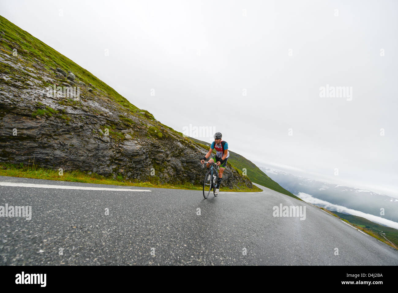 Triathlete climbs towards the top of Aurlandsfjellet at 1300m above sea level and Sognefjorden fjord where he started. Stock Photo