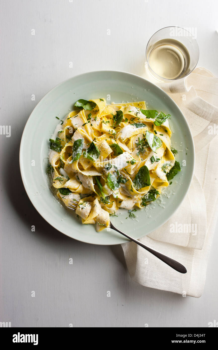 A plate of pappardelle pasta with creamy ricotta, baby spinach, fresh herbs and black pepper. Stock Photo