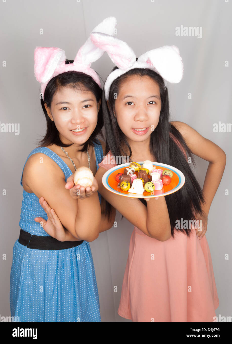 Cute Asian bunny girls hold plate of Easter eggs, chocolate and rock egg. Stock Photo