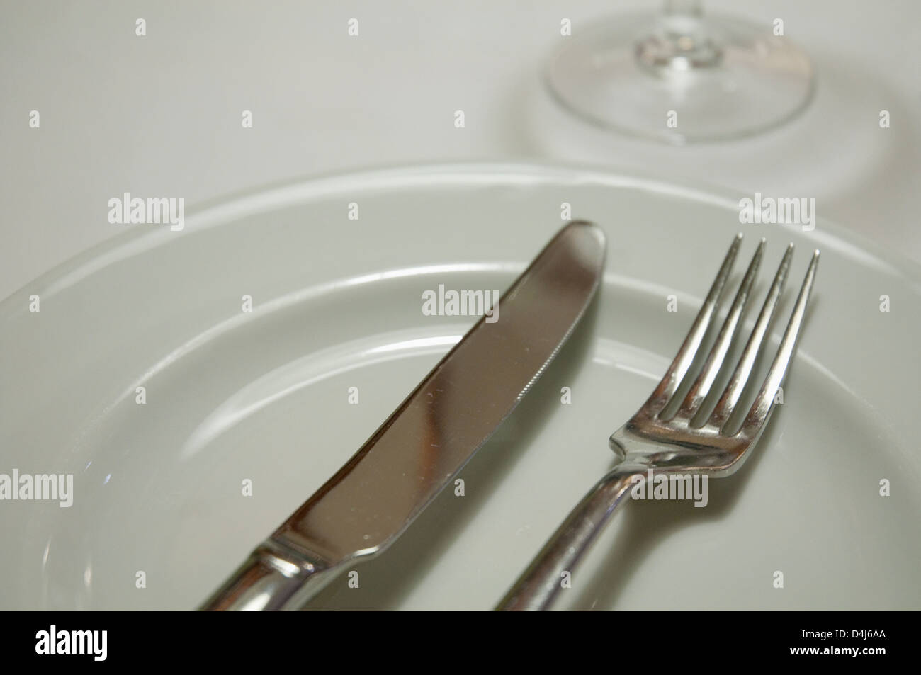 Fork and knife on an empty plate. Close view. Stock Photo