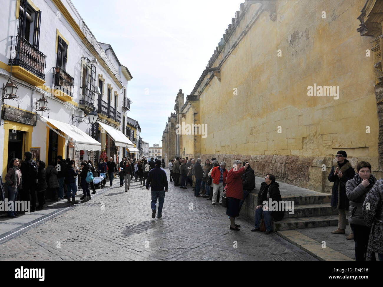 Mid-Day on a Sunday people crowd a street outside the Mezquita Mosque-Cathedral in Cordoba, Andalusia, Spain, and consume drinks Stock Photo