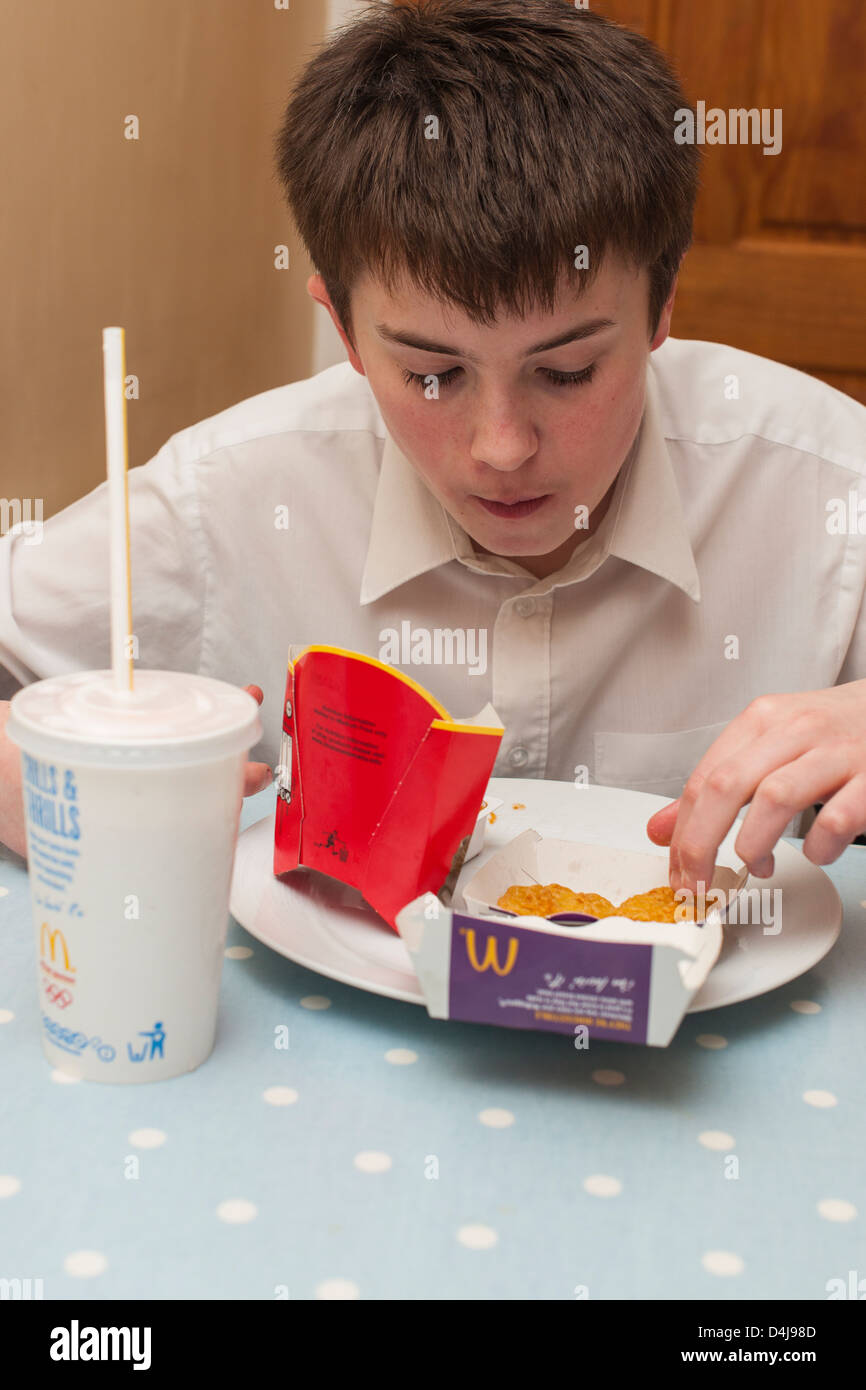 A thirteen year old boy eating a Mcdonalds meal at home in the Uk Stock Photo