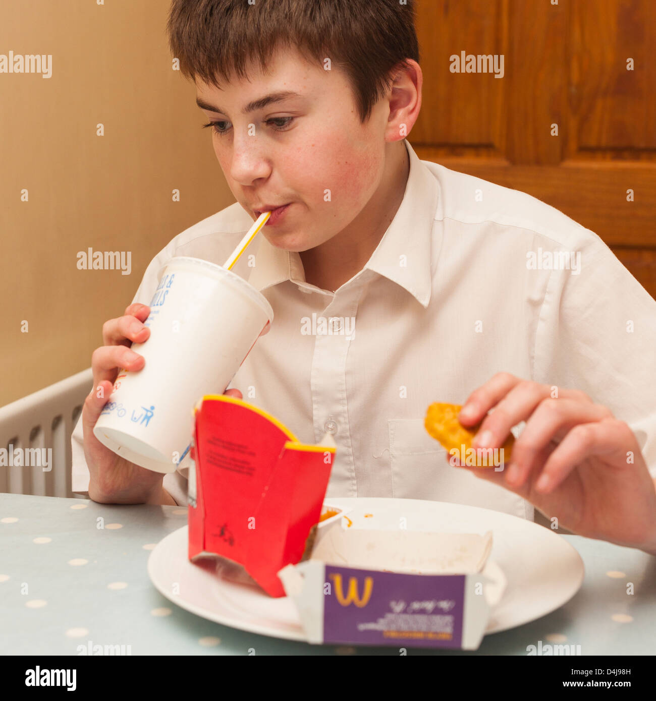 A thirteen year old boy eating a Mcdonalds meal at home in the Uk Stock Photo