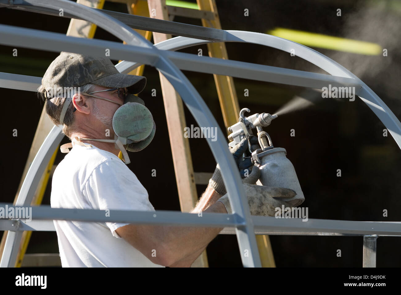 Construction worker spray paints while wearing respiratory safety equipment to protect himself