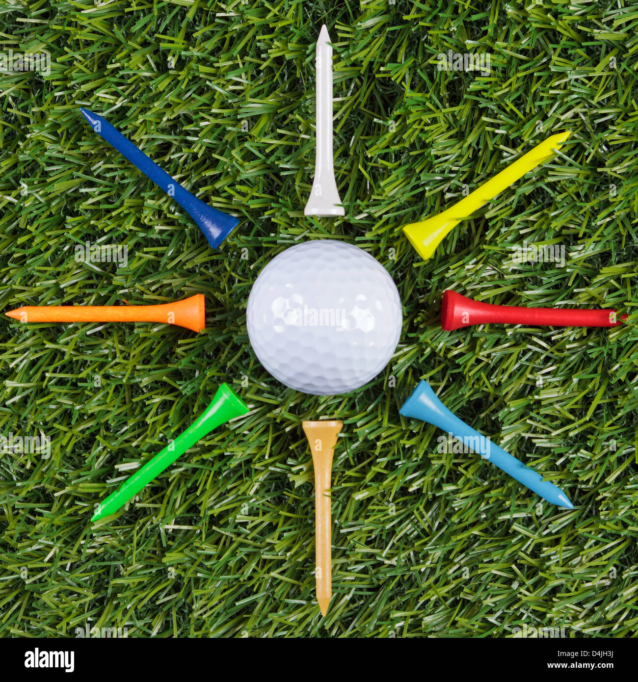 Golf ball with wooden tees arranged around it. Stock Photo