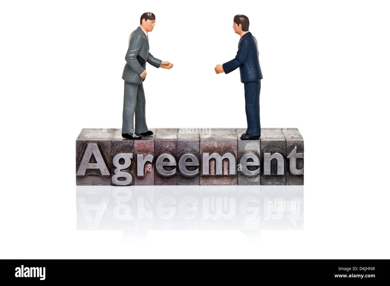 Hand painted businessmen figurines and the word Agreement in old metal letterpress isolated on a white background. Stock Photo