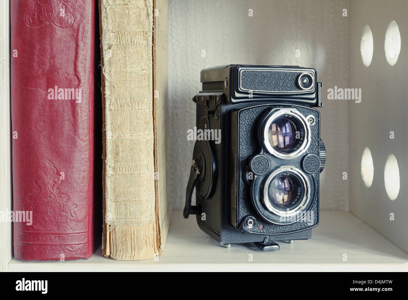 vintage TLR photo camera with old books on the white shelf Stock Photo