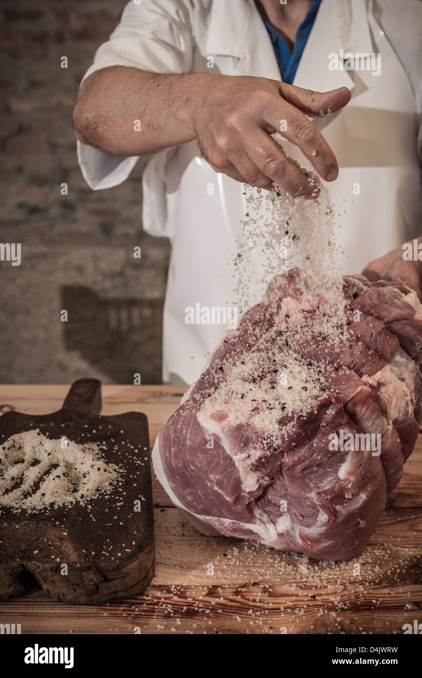 Butcher spicing meat in shop Stock Photo