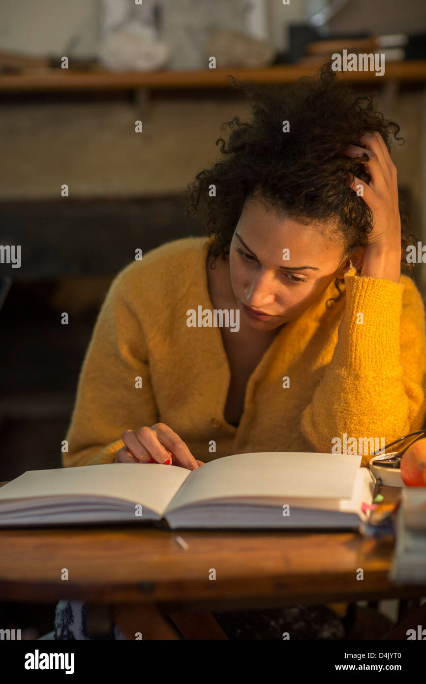 Woman reading book at desk Stock Photo