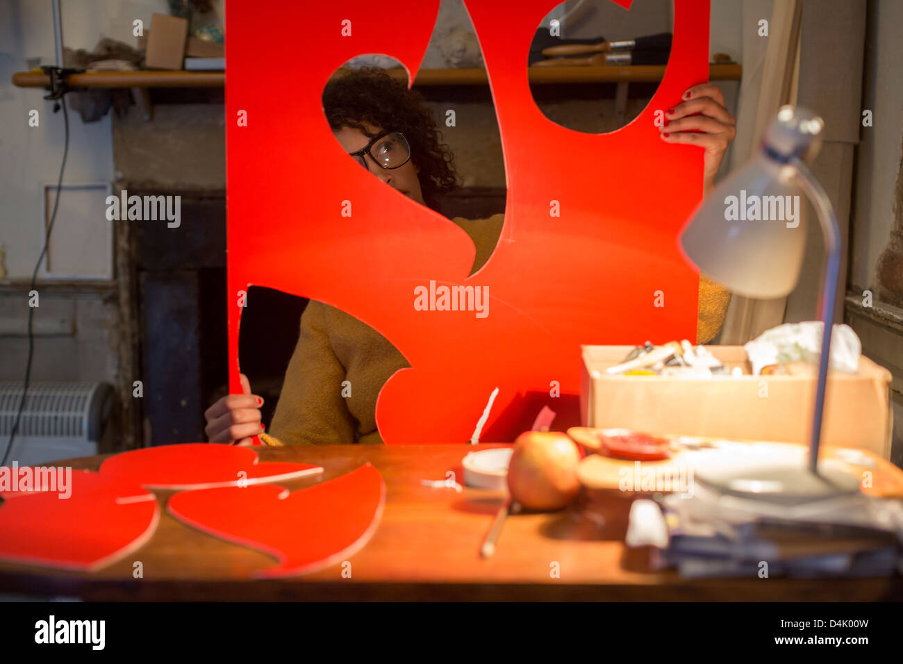 Artist cutting out red cardboard Stock Photo