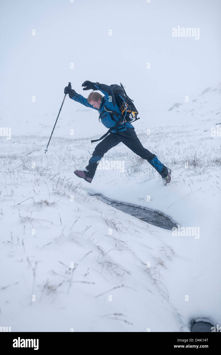 Hiker jumping in snowy landscape Stock Photo