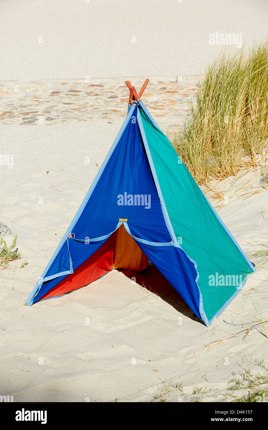 Multi coloured teepee tent grass beach sand sea Stock Photo