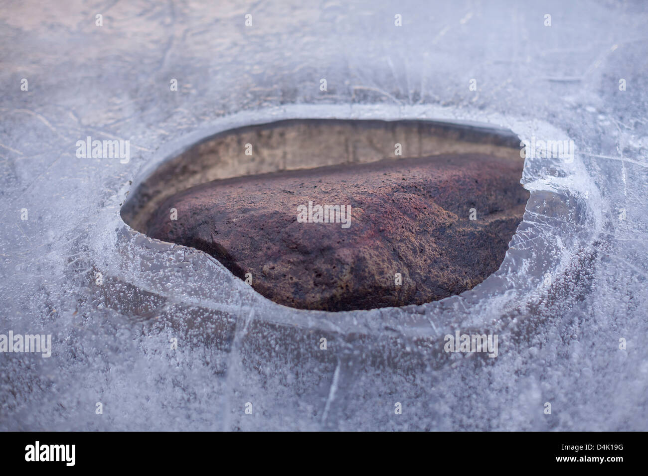 Hole in layer of ice on rural lake Stock Photo