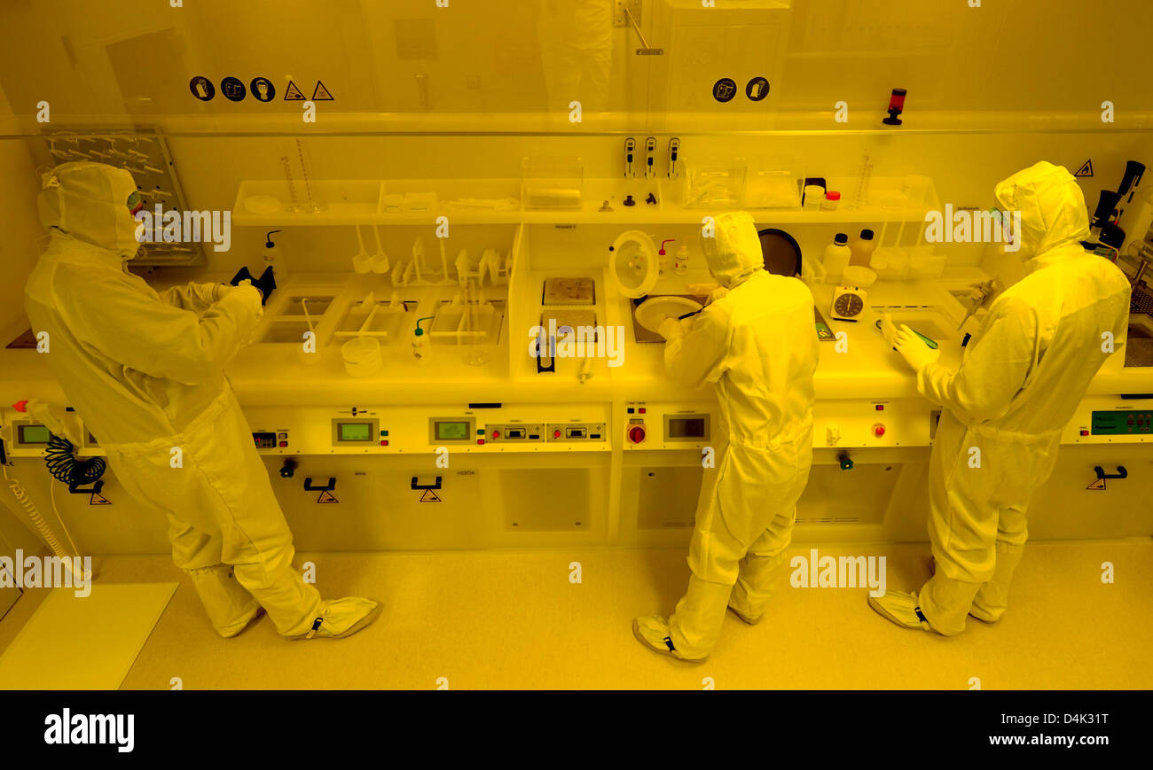 Scientists work at a wet bench in the clean room at the Centre for Biotechnology and Biomedicine (BBZ) of the University of Leipzig, Germany, 09 March 2009. Here, 3D biochips, which are used for the diagnosis of tumour tissue at medical facilities and research laboratories, are tested and lacquered for impedimetric multi-channel measurement under yellow light. The 3D micro cavity c Stock Photo