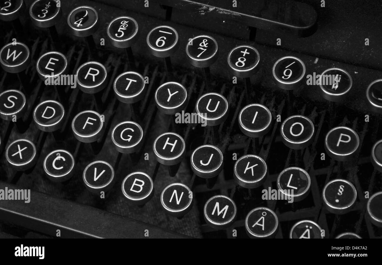 Small typewriter with keyboard in focus over a page of a book. Decoration  item. Concepts of reading, writing, old times, past. Close up. Blurred  background. Stock Photo