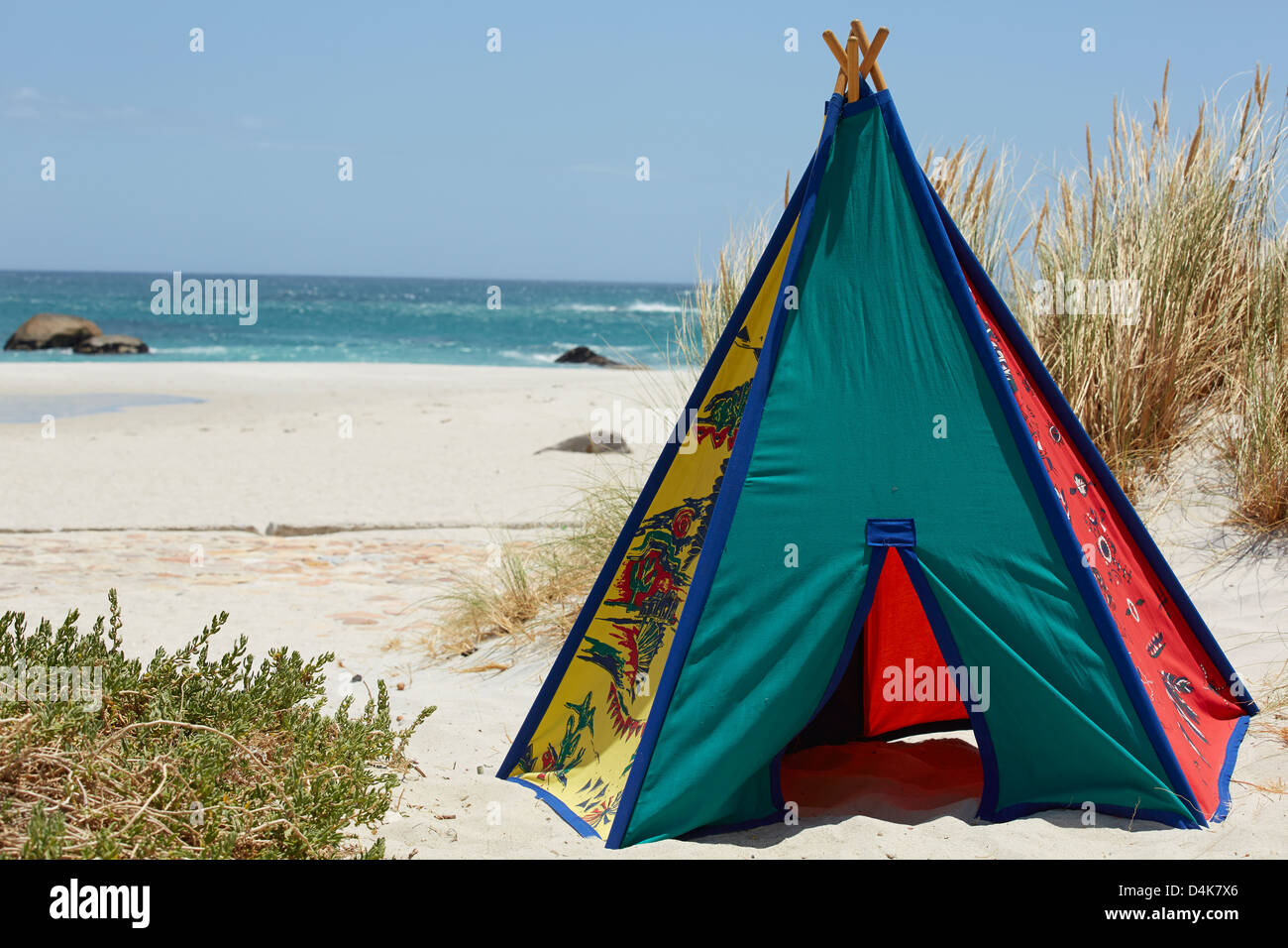 Multi coloured teepee tent grass beach sand sea Stock Photo
