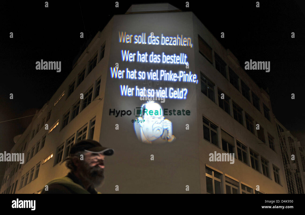 A light installation of artist Oliver Bienkowski is projected to the front of the Hypo Real Estate headquarters in Munich, Germany, 10 April 2009. The sentence ?Wer soll das bezahlen, Wer hat das bestellt, Wer hat so viel Pinke-Pinke, Wer hat so viel Geld?? (lit. ?Who will pay for this, who ordered this, who has this much cheeze, who has this much money??) is written above a carica Stock Photo