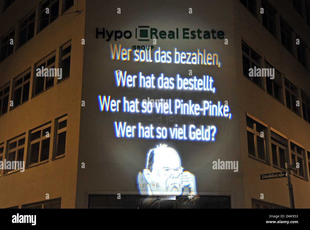 A light installation of artist Oliver Bienkowski is projected to the front of the Hypo Real Estate headquarters in Munich, Germany, 10 April 2009. The sentence ?Wer soll das bezahlen, Wer hat das bestellt, Wer hat so viel Pinke-Pinke, Wer hat so viel Geld?? (lit. ?Who will pay for this, who ordered this, who has this much cheeze, who has this much money??) is written above a carica Stock Photo