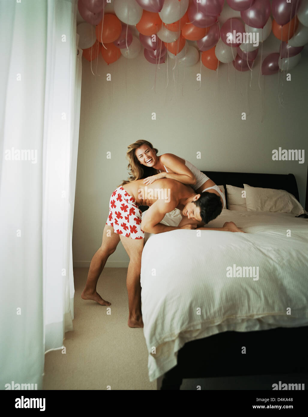Smiling couple wrestling on bed Stock Photo