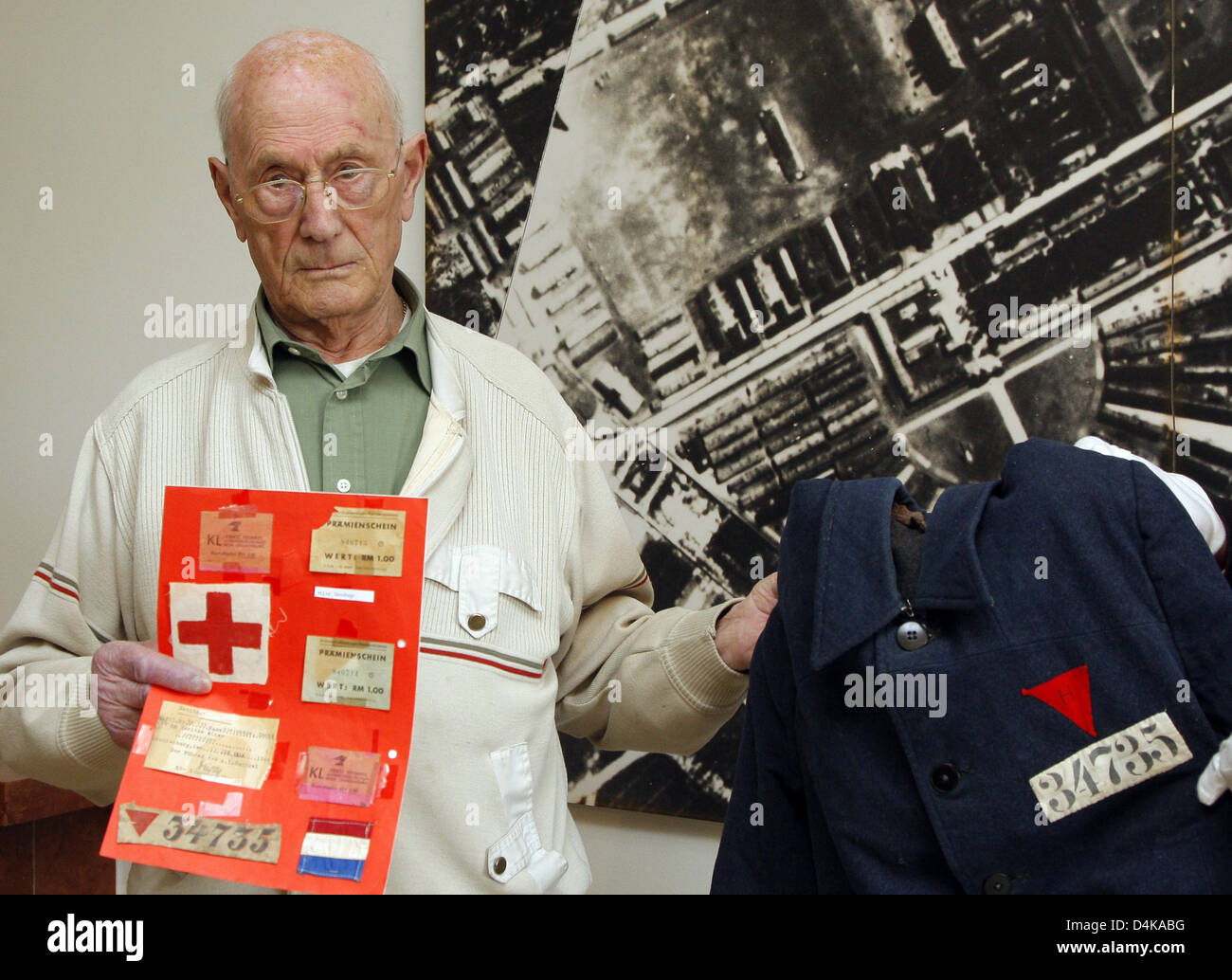 Hans Steinhage, a survivor of the concentration camp Sachsenhausen, holds his prisoner?s winter jacket and several personal souvenirs while standing in front of an aerial photo of the camp in Oranienburg, Germany, 17 April 2009. The 89-year-old was a political prisoner in Sachsenhausen from 1940 to 1945. After 64 years he now returned from the Netherlands to the place of his suffer Stock Photo