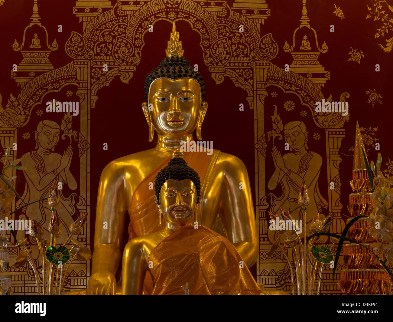 Golden Buddha statues against a ruby red background Stock Photo