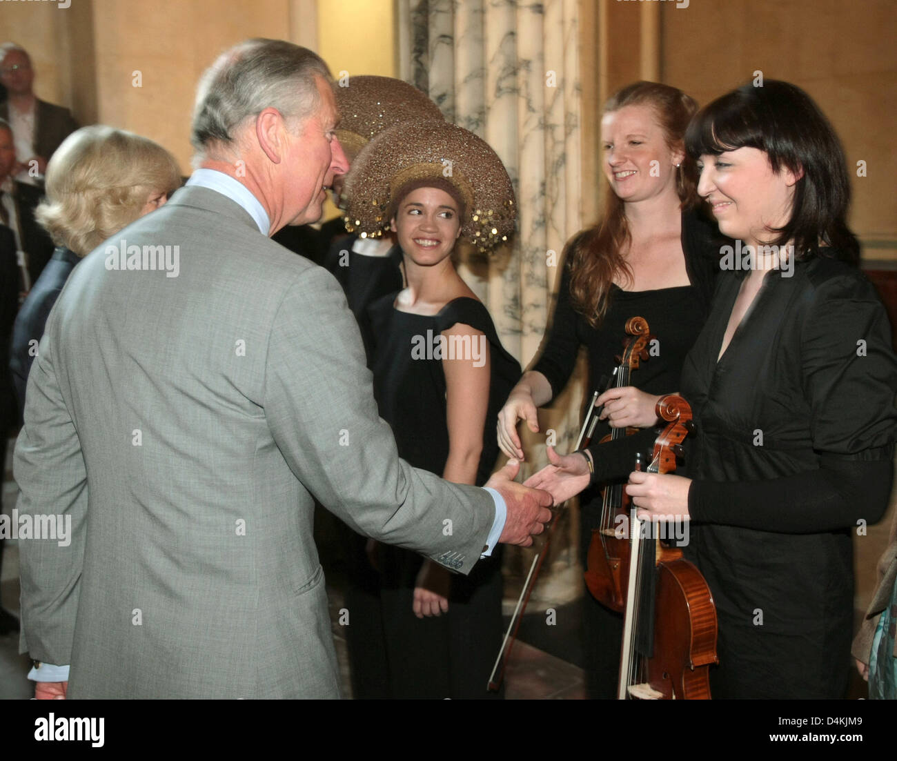 Prince Charles, Prince of Wales (L) offers a handshake to musicians as