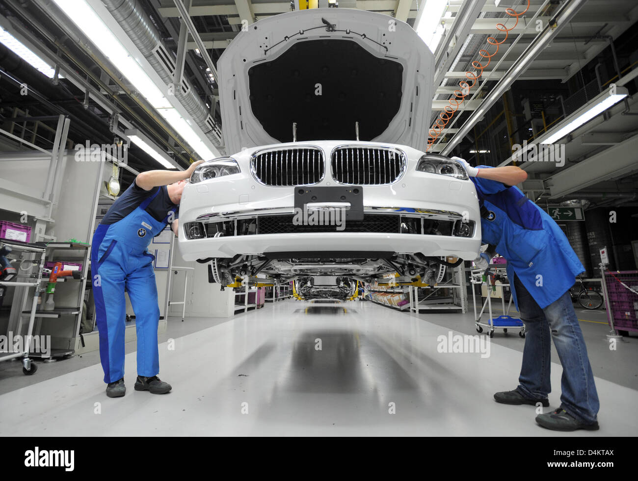 Staff members assemble the front spoiler of a 7 Series BMW in the BMW ...
