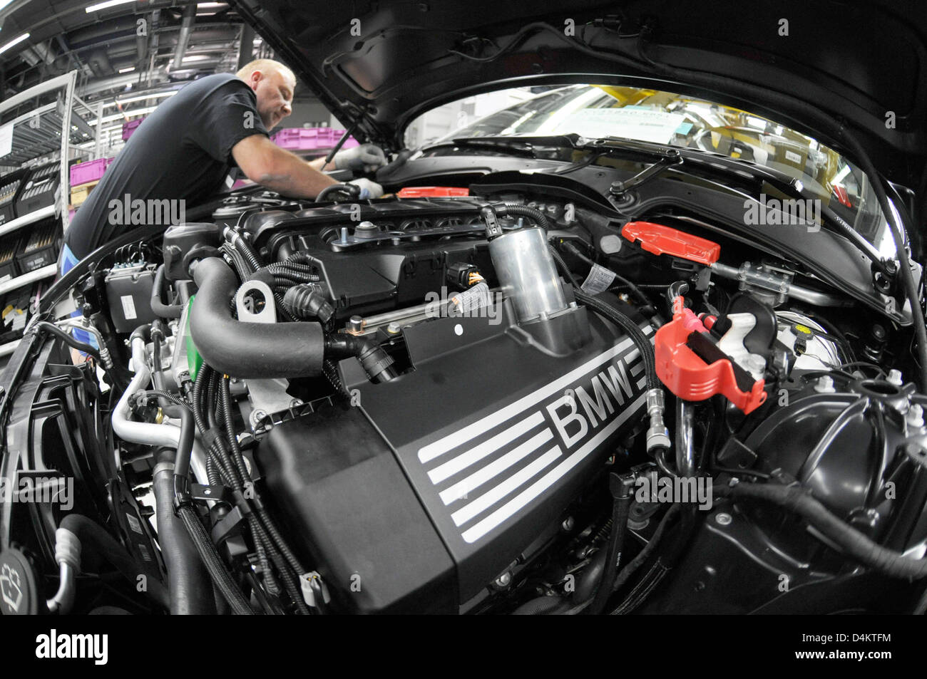A staff member works at the engine of a BMW 7 Series in the BMW factory ...