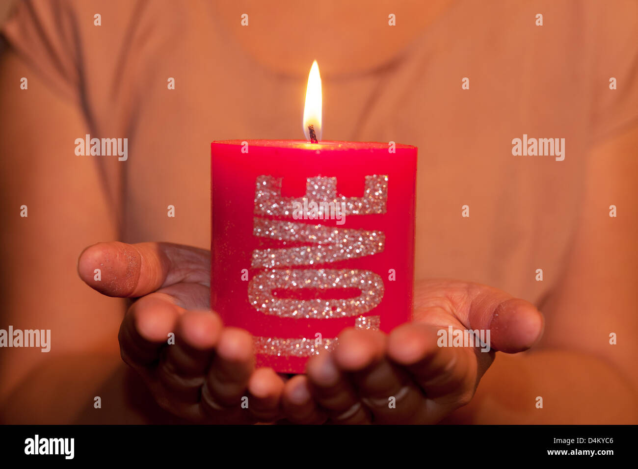 Two hands holding a big red candle Stock Photo