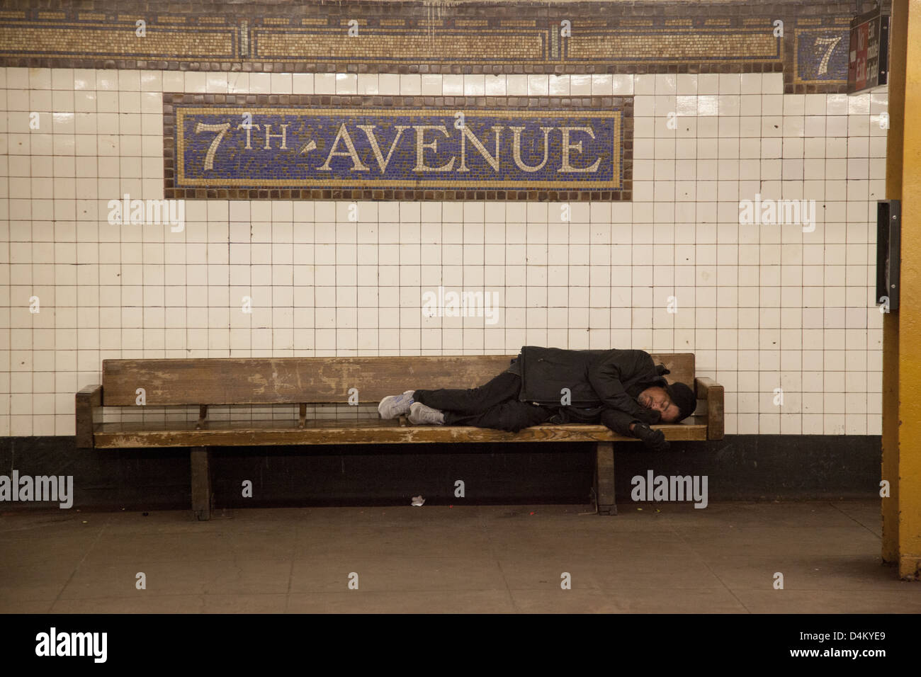 Man sleeps on a bench on the platform at the 7th Avenue subway Station in Brooklyn, New York. Stock Photo