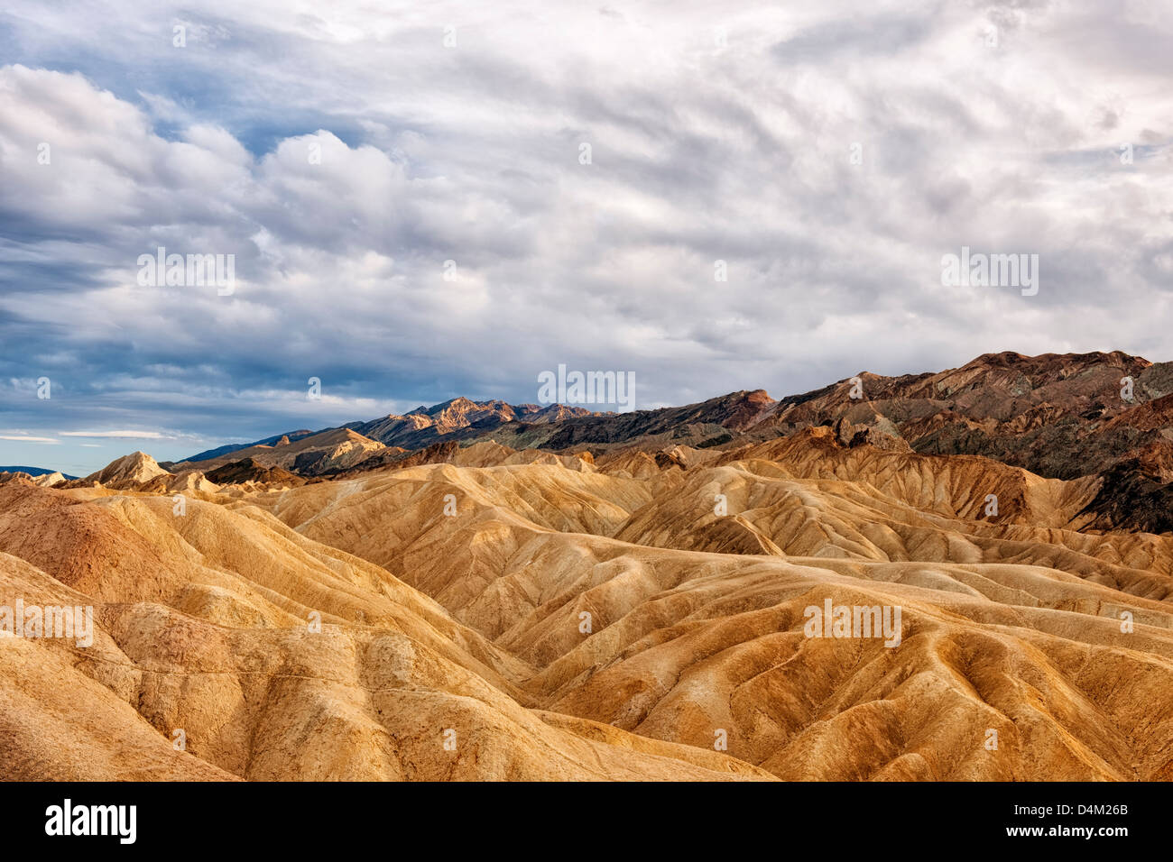 Dappled evening light bathes the badlands of Golden Canyon and California's Death Valley National Park. Stock Photo