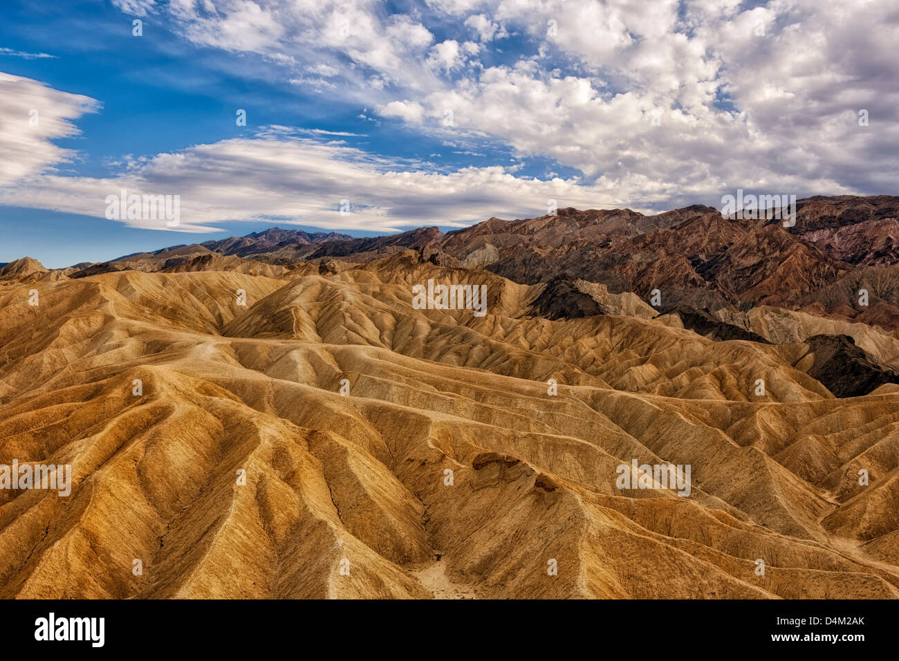 Afternoon clouds float over the badlands of Golden Canyon and California's Death Valley National Park. Stock Photo
