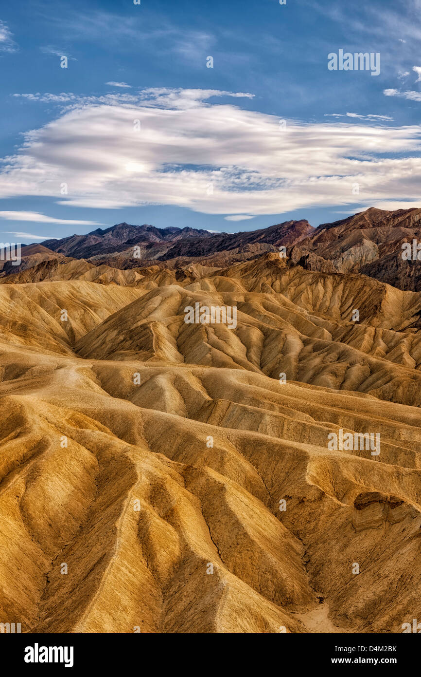 Afternoon clouds float over the badlands of Golden Canyon and California's Death Valley National Park. Stock Photo