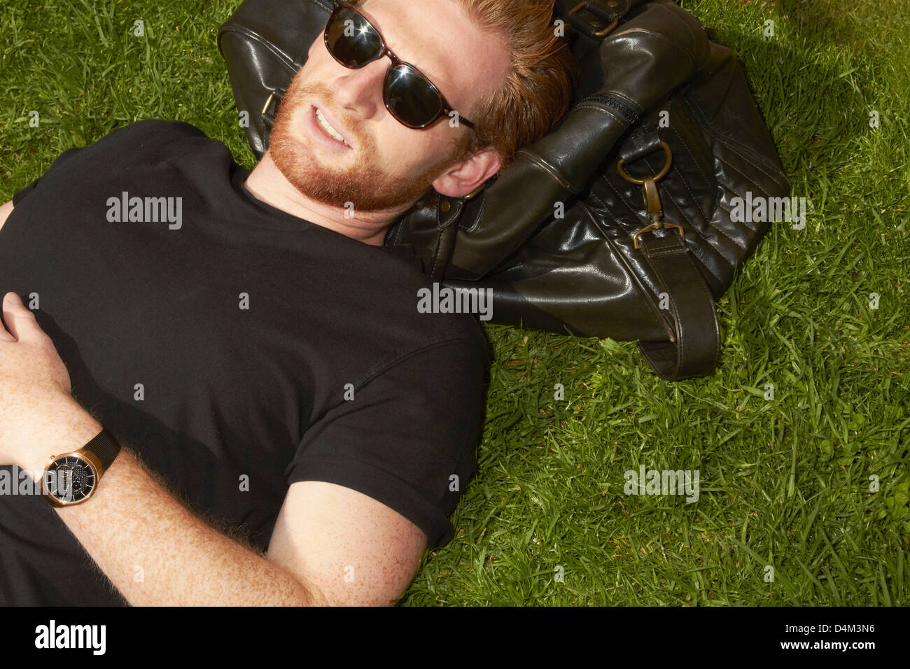 Man laying on bag in grass Stock Photo