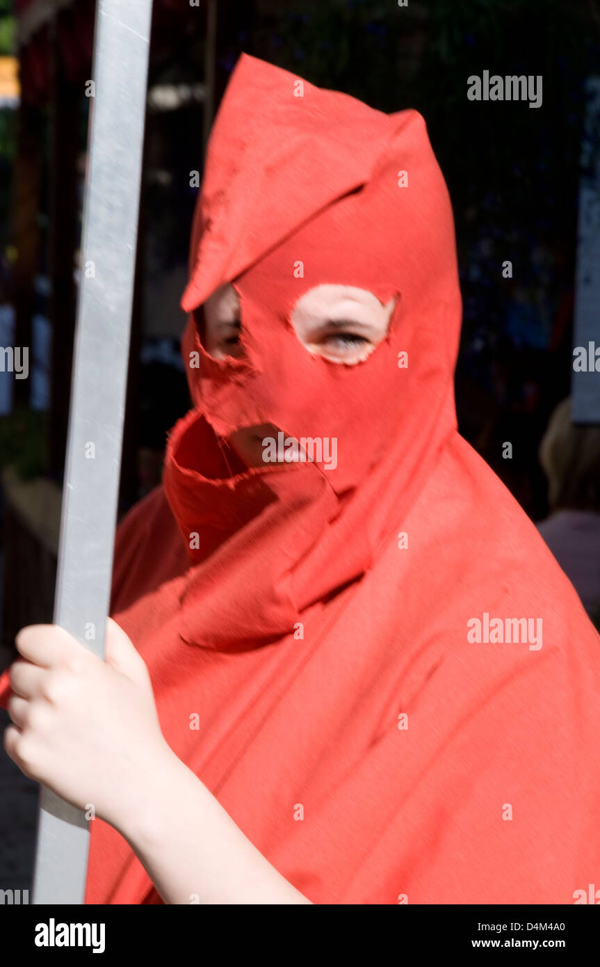 A young girl wearing a medieval executioner's hood, holding a billboard, advertising a local torture chamber museum, a tourist attraction in Viru Stock Photo