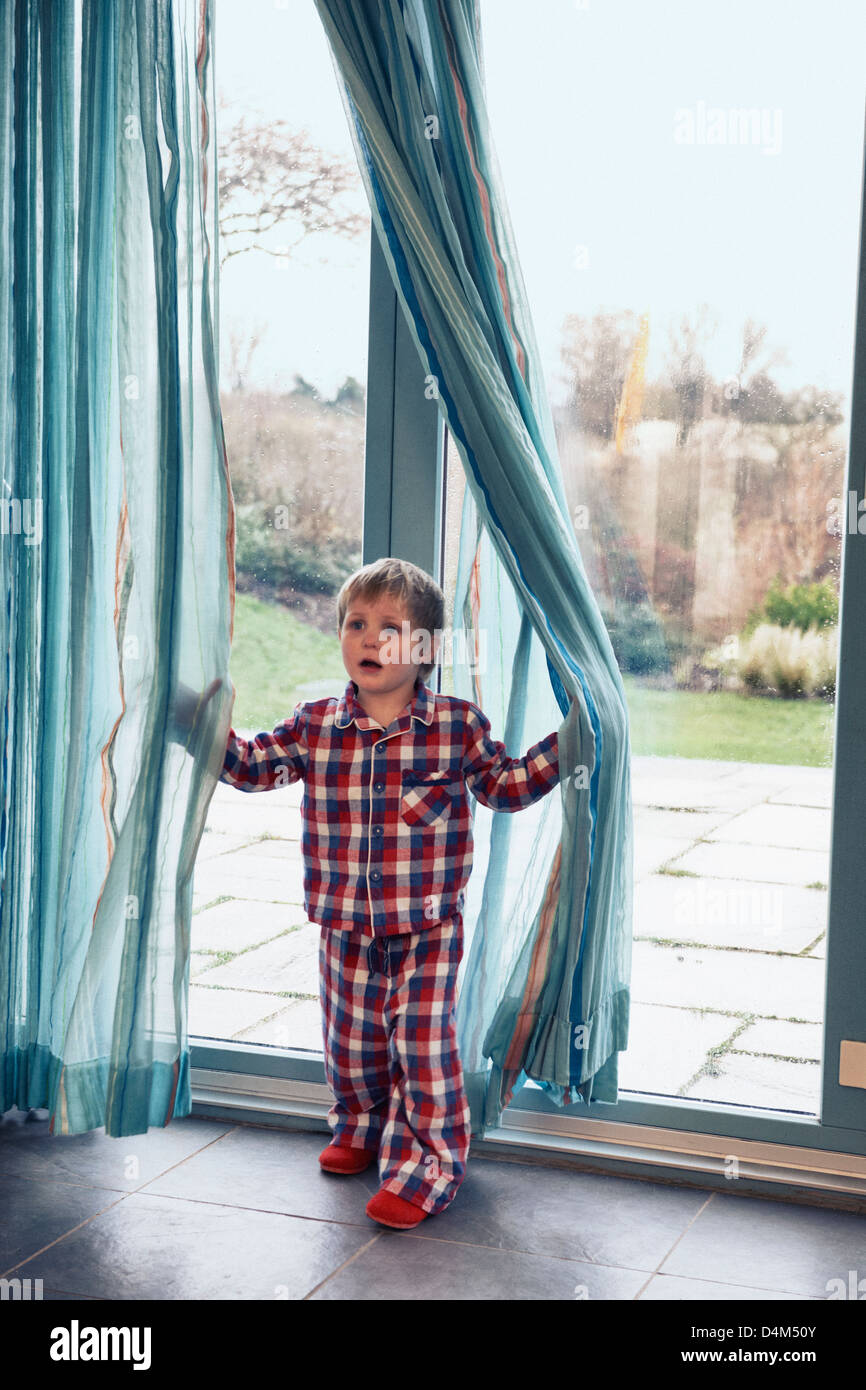 Boy in pajamas playing in curtain Stock Photo