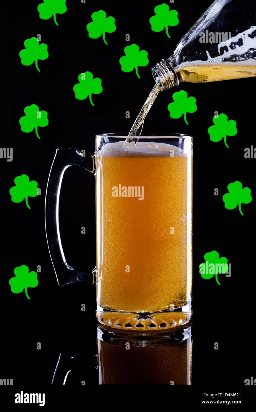 A studio image of a mug of beer with shamrocks in the background. Stock Photo