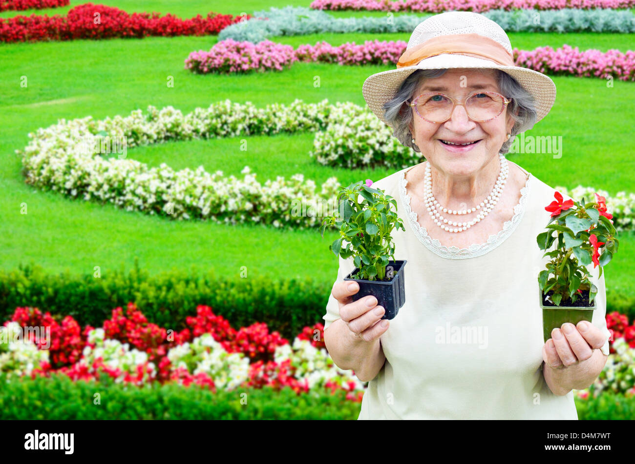 Happy senior woman holding flowers in garden Stock Photo - Alamy