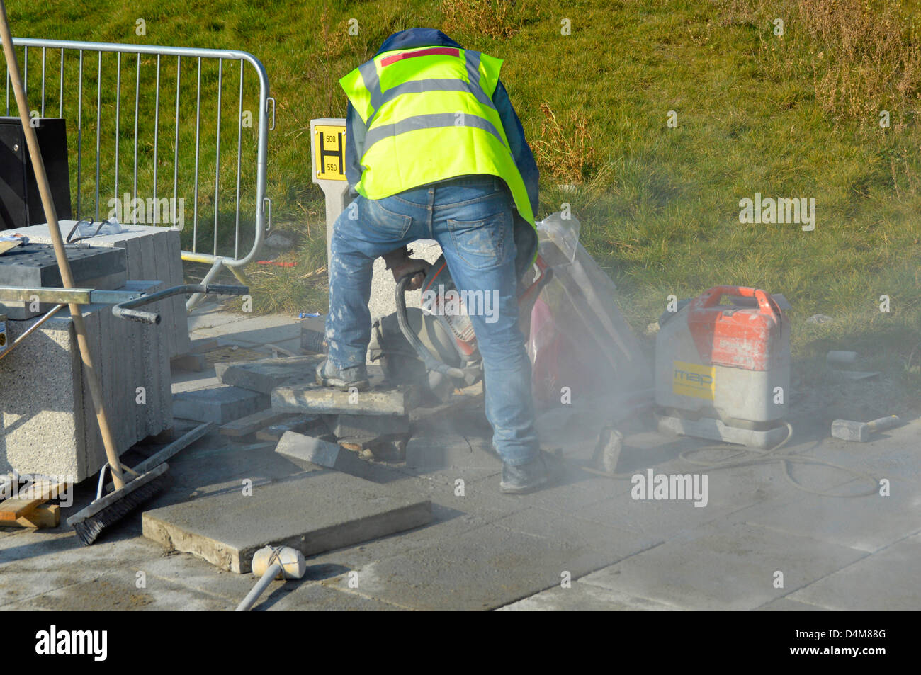 Workman using a portable masonry saw machine for cutting paving slabs (name removed from jacket) Stock Photo