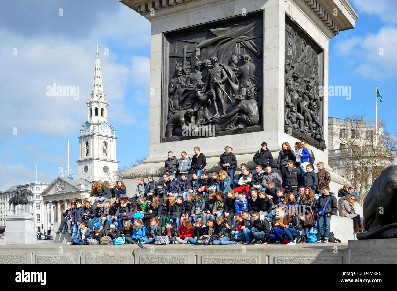 School visit to London for large party of kids posing for group photo on Nelsons Column plinth Stock Photo