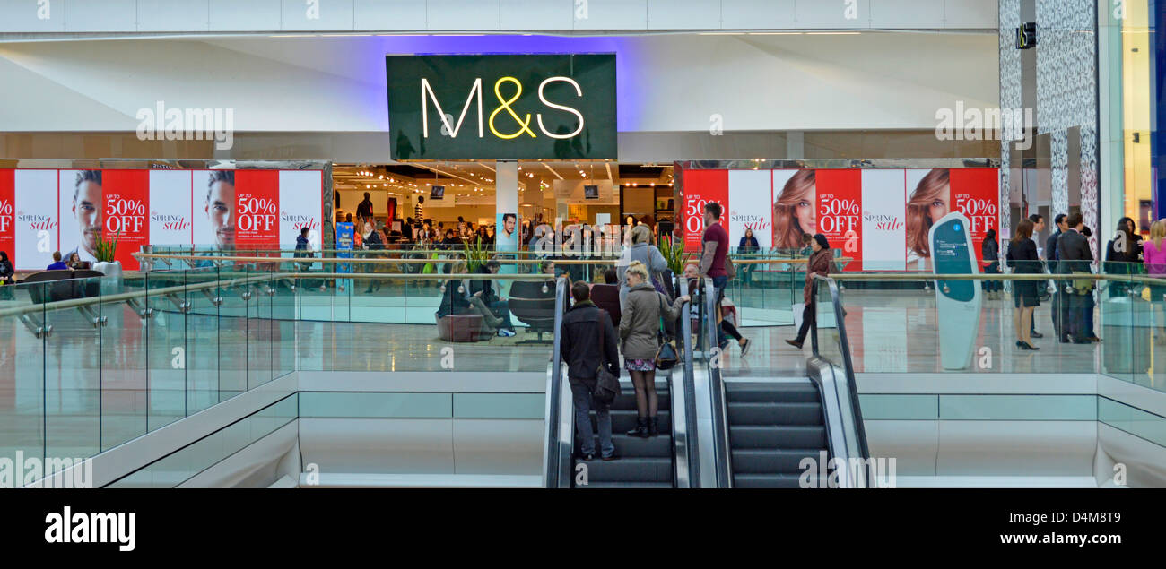 Marks and Spencer shop front with 50% promotion window posters and shoppers on escalators at the Westfield centre shopping malls Stock Photo
