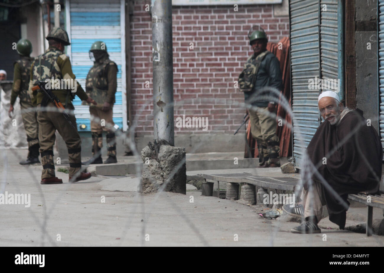 March 16, 2013 - A kasmiri muslim taking rest on the road as Indian paramilitary soldiers stands guard  during  curfew at old city  in srinagar, the summer capital of indian kashmir , on 16/3/2013,Curfew was imposed on Thursday after a 34-year-old youth was killed when Indian paramilitary soldiers  allegedly opened fire after coming under attack by a group of stone pelters in the Zoonimar area..Photo/Altaf Zargar/Zuam Press (Credit Image: © Altaf Zargar/ZUMAPRESS.com) Stock Photo