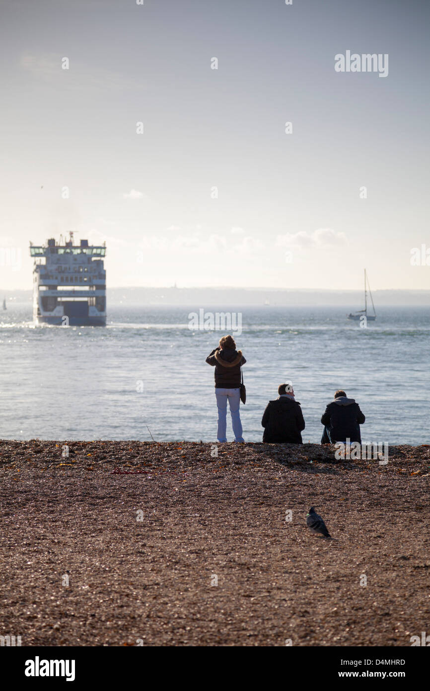 People on Southsea Beach in Portsmouth looking out to a Wightlink car ferry in the Solent heading to Fishbourne, Isle of Wight Stock Photo
